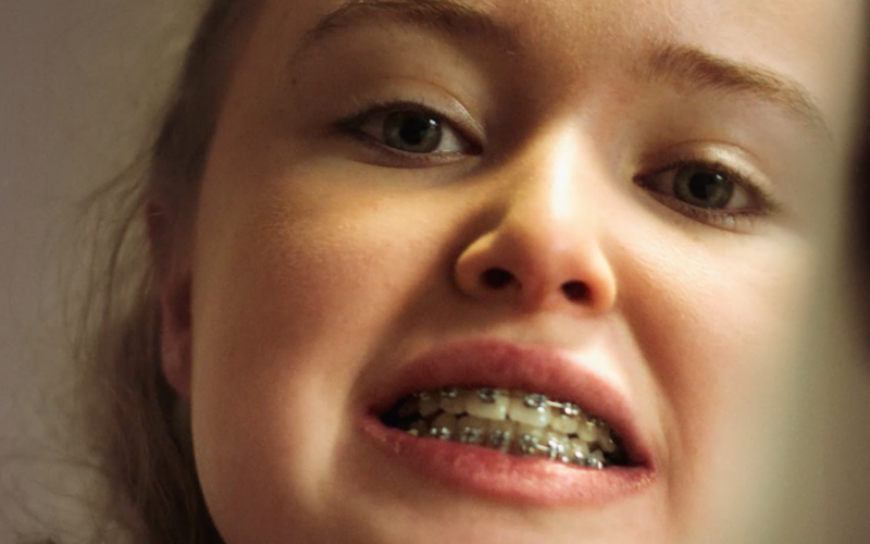 Kelly looking at her new braces in the mirror