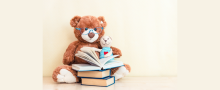 Two teddies reading a pile of books