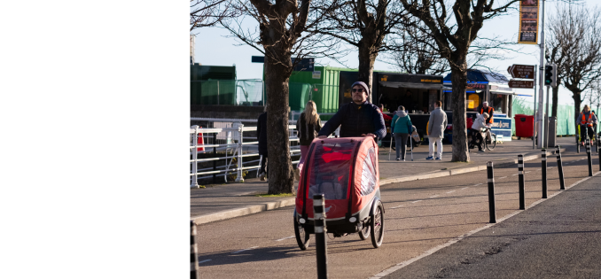 people walking on sidewalk, cargo bike,and row of trees