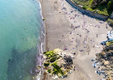 looking down on beach with sand, water and people