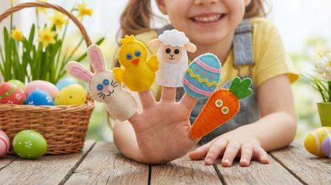 A child holding up five finger puppets on one hand.