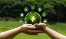 Hands holding a green sphere with an electricity symbol, surrounded by icons representing recycling, renewable energy, carbon reduction, sustainable industry, transport and community action.