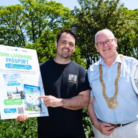 Brian Hanratty, owner of Happy Out Cafés and An Cathaoirleach, Councillor Jim Gildea DLR holding up plagues advertising the Dun Laoghaire passport