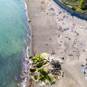 looking down on beach with sand, water and people