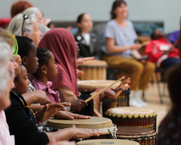 Children and adults playing djembe drums
