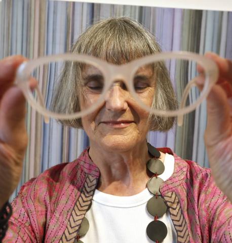 Artist Maggie O'Dwyer standing in front of her painting Ley Lines with her glasses held close to the camera