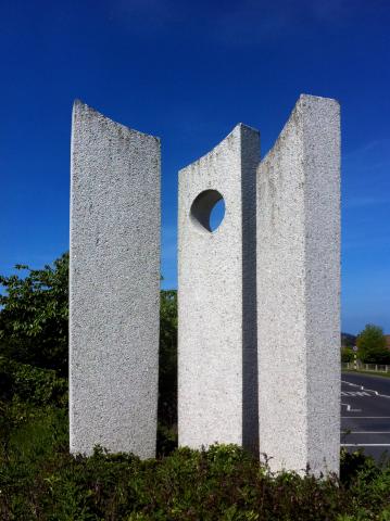 sculpture of three standing stones. the middle has a circle cut out near the top