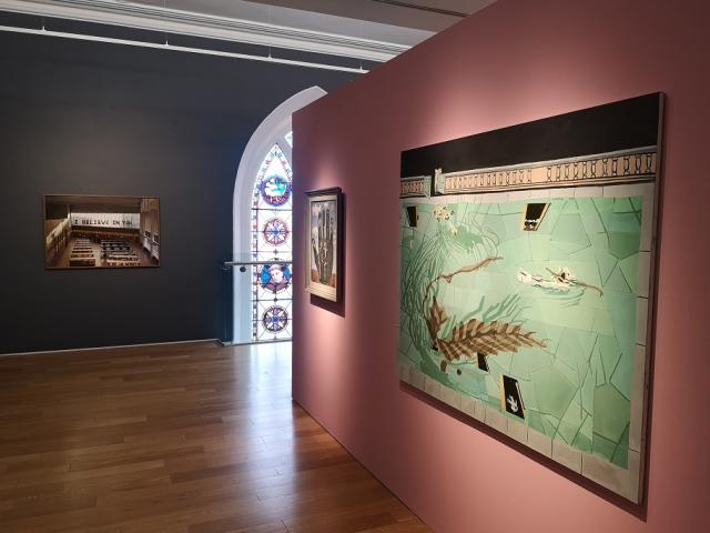 Paintings on a pink and grey wall in The Highlanes Gallery