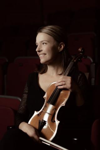 musician Lidia smiling while holding a violin