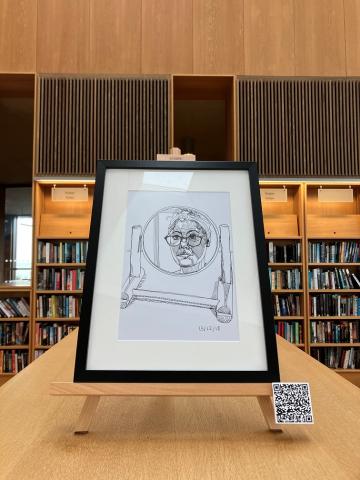 Self portrait drawing in a round mirror. drawing is in a black frame on an easel on top of a library bookshelf