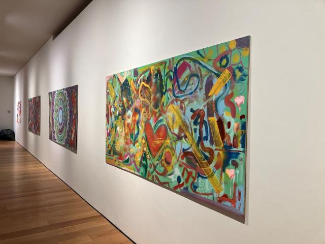 3 large boards on a long wall. The boards have bright colourful abstract mural paintings