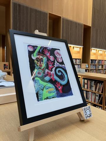 A colourful framed artwork sits on top of 3 wooden chest height bookcases in the Lexicon Library