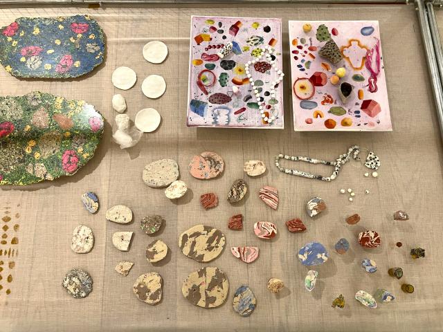 Photo looking down on lots of small colourfull pieces of clay laid out on top of a cream coloured cloth.