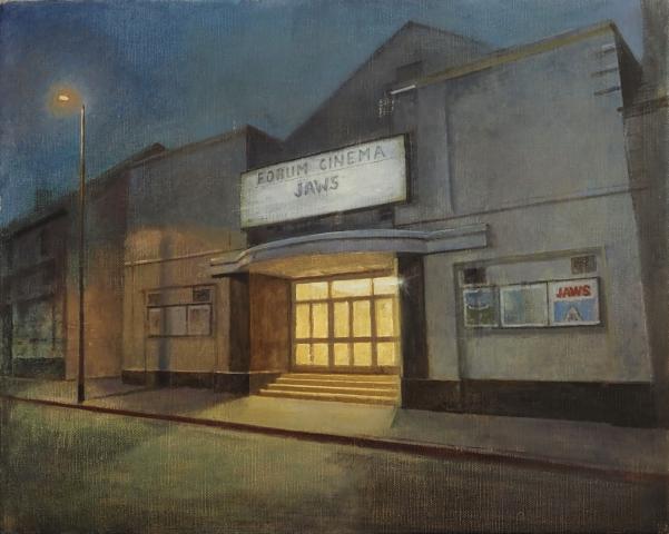 painting of the front of the old Forum cinema in Dún Laoghaire. The angle is a slight side view showing the main entrance at twilight, with light spilling onto the street from the cinema foyer. It is a warm yellow light and there is a streetlamp to the left hand side of the building too. The colour palette is soft with greys for the building and blue/purple sky.