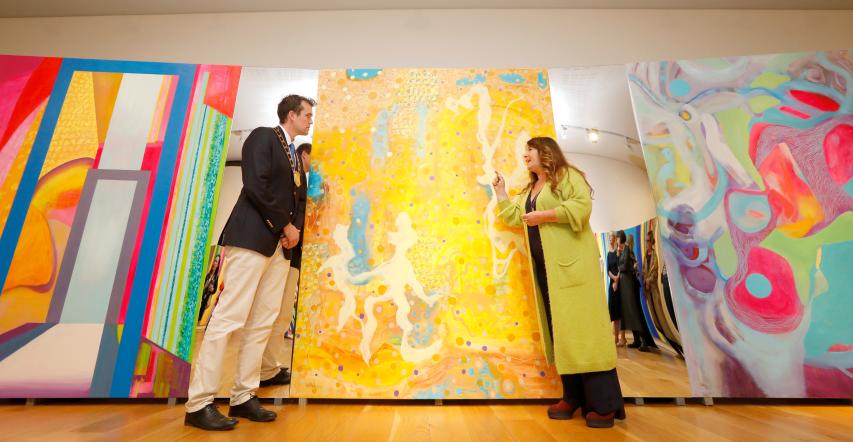 Cllr Pierce Dargan and Karen Ebbs stand either side of a large yellow abstract painting