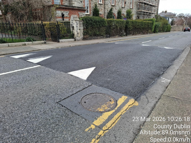 Street with manhole cover and yellow directional arrow.