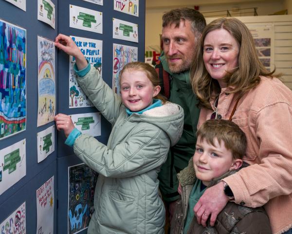 girl and boy with parents lookiing at competition posters
