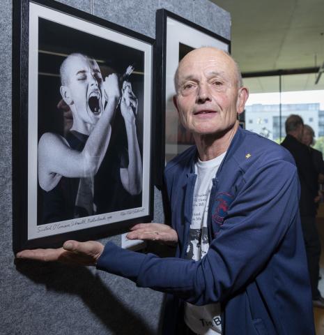 Rob Verhorst stands with his picture of Sinead O'Connor. Sinead is singing into a microphone.
