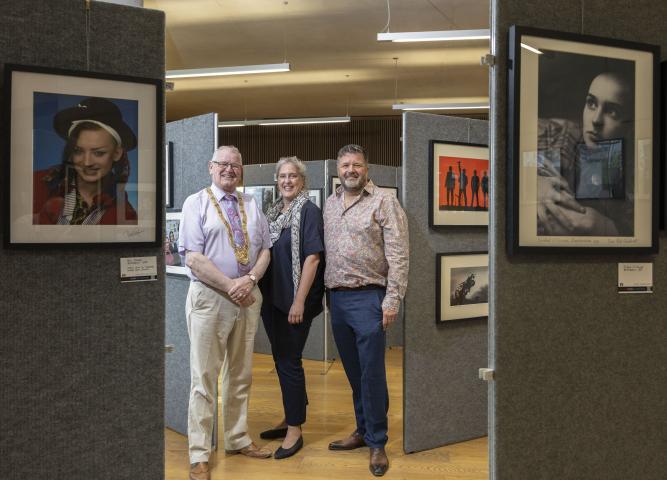 An Cathaoirleach Councillor Jim Gildea, Dún Laoghaire-Rathdown County Council, Dutch Deputy Ambassador, Nora Dessing and Ramon Muntjewerff, exhibition organiser stand in the middle of the exhibition with multiple photographs around them.