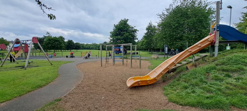A picture of Carysfort Park Playground with an orange slide, a pathway and some greenery