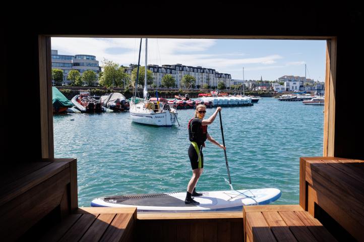 person on paddle board view through sauna window