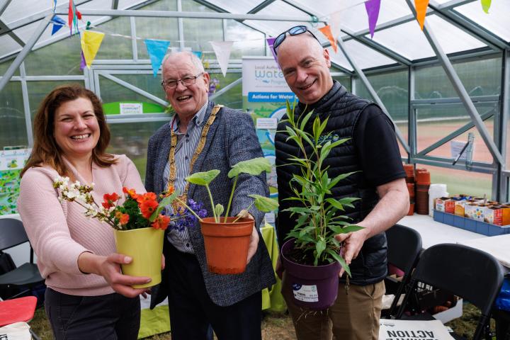 three people holding plants in a greenhouse