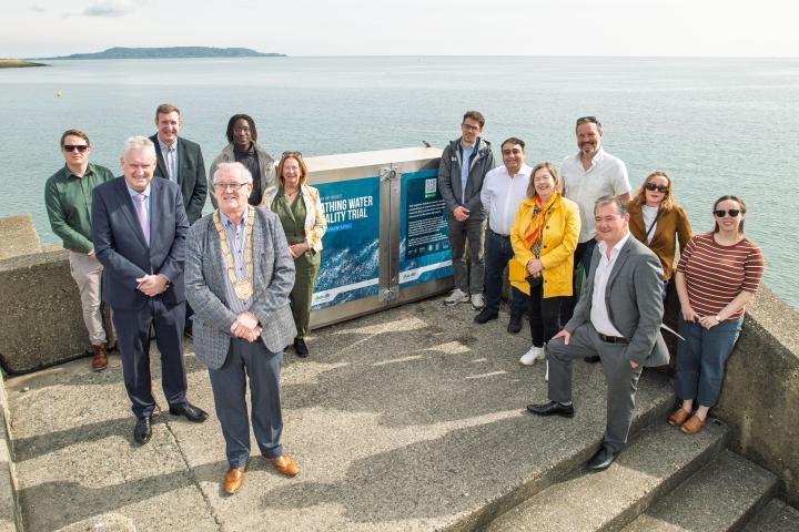 Group of men and women in front of kiosk with sea in background