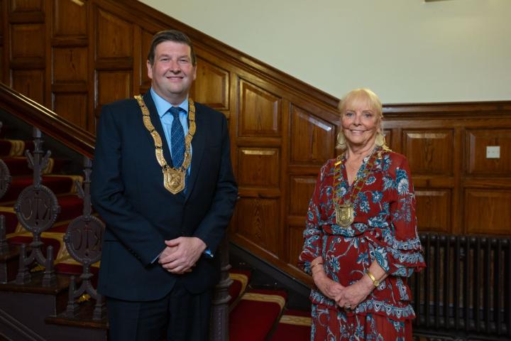 man and woman standing in front of stairs wearing chains of office
