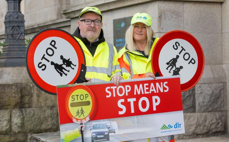Two school wardens hold up signs saying 'stop means stop' outside the County Hall in Dun Laoghaire