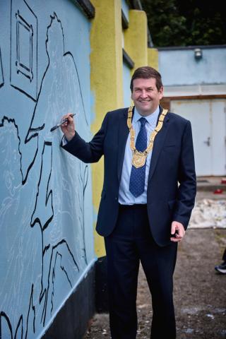 An Cathaoirleach Cllr Barry Saul with the mural at Blackrock Scout Den