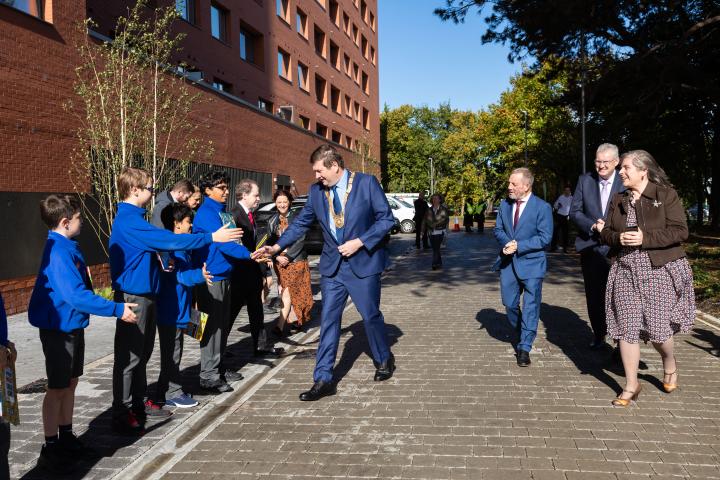 Cllr Barry Saul, Cathaoirleach of Dún Laoghaire-Rathdown County Council walking towards crowd of school kids outside red bricked building