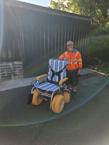 a man standing beside a terrawheels wheelchair with his right hand on top