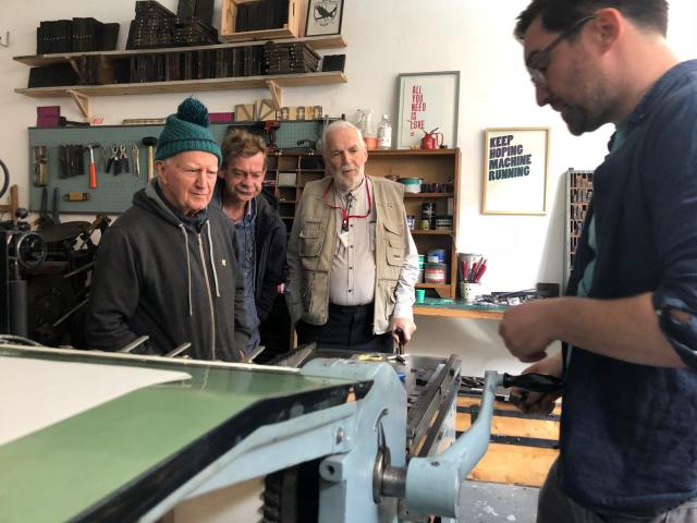 photograph of a group of 3 men from the Men's Shed network visiting Dave Darcy in his letterpress studio
