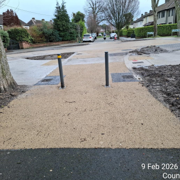 Paved walkway with two poles in the center, providing guidance and support for pedestrians.